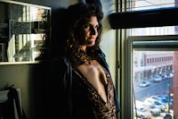 a woman in a leopard print dress leaning against a window