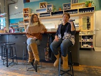 two women sitting on stools in a bar
