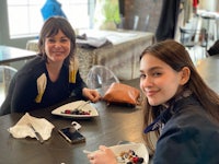 two women sitting at a table with plates of food