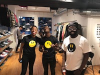 three people standing in a store with smiley face t - shirts