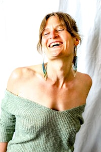 a woman laughing in a green sweater
