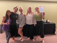 four women posing for a photo in front of a table