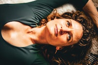 a woman with curly hair laying on a rug