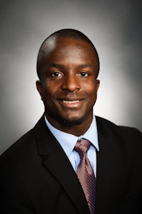 a black man in a suit and tie smiles for the camera