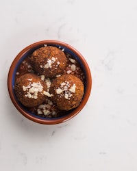 three meatballs in a bowl on a white table