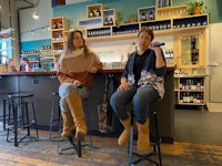 two women sitting on stools in a bar