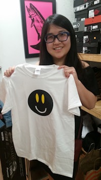 a woman holding up a t - shirt with a smiley face on it