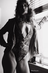 a woman in a leopard print swimsuit posing in front of a window