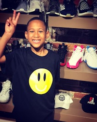 a young boy posing for a photo in front of a rack of shoes